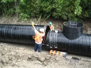 Polymer-coated corrugated steel storm sewer system with access structure during installation
