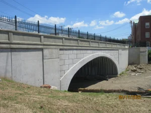 Installation of a deep corrugated structural plate buried bridge inside the existing concrete arch.