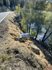 New corrugated steel culvert installed along a wooded slope during Caltrans drainage improvements in Trinity County.