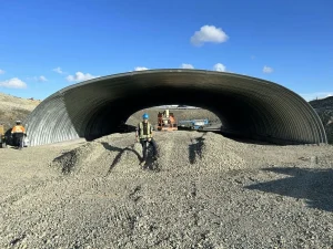 Structural plate arch installation showing roadway construction and backfill operations.