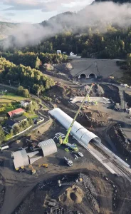 Crane placing preassembled corrugated steel bridge sections over an active railway.
