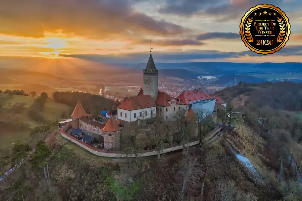 A panoramic view of Leuchtenburg Castle overlooking the valley with the enclosed galvanized steel incline lift extending up the hillside.
