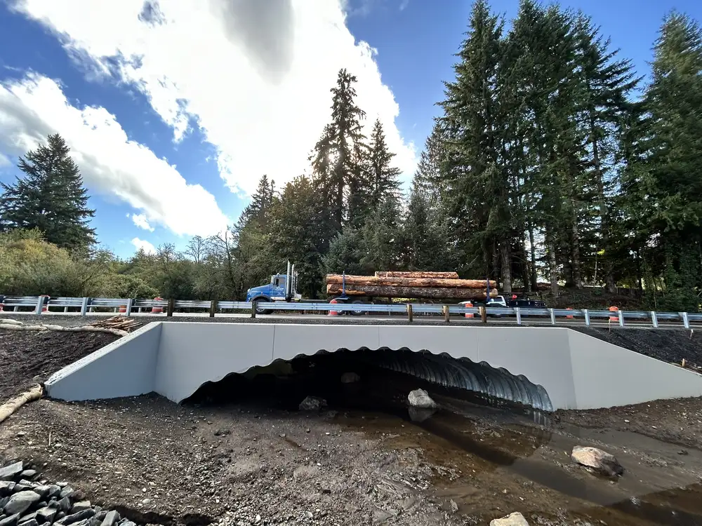 A logging truck crosses the completed structural steel plate bridge on Oregon Highway 47, a critical route for the local timber industry.