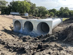 Burke SD Triple 120in CHS (1)_resized Completed triple-barrel corrugated steel culvert with prefabricated metal headwalls along County Road 27 in Burke, South Dakota.
