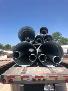 Multiple corrugated steel pipe sections nested together on a flatbed trailer for efficient transportation.